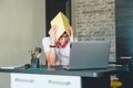 Sad tired teenager in white shirt sitting behind desk in kitchen  near laptop and study. Depressed Boy in earphones makes homework Royalty Free Stock Photo