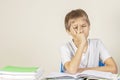 Sad tired upset schoolboy covering face with his hands sitting at table with pile of school books and notebooks at home Royalty Free Stock Photo