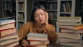 Sad tired woman girl student bored at desk with books in university library lazy unmotivated asian female preparing for