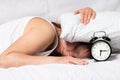 Sad tired woman waking up in the morning with alarm clock. Girl doesn` t want to wake up