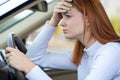 Sad tired yound woman driver sitting behind the car steering wheel in traffic jam