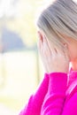 Sad tired young beautiful blonde woman with her face in her hands being frightened, having anxiety or headache migraine Royalty Free Stock Photo