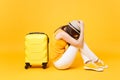 Sad traveler tourist woman in summer casual clothes, hat sit near suitcase on yellow orange background. Female Royalty Free Stock Photo