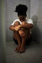 Sad, unhappy and depressed student sitting alone on the floor of a bathroom in school. Lonely, upset and depressed teen