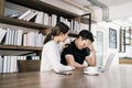 The sad unhappy handsome man sitting in front of a laptop, holding his forehead while having a headache with a woman cheering up