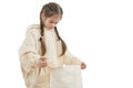 Sad, unhappy little girl with pigtails dressed in beige hoodie holds shoping package in hands and looking inside Royalty Free Stock Photo