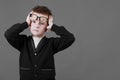 Sad unhappy schoolboy in eyewear having painful look, holding hand on his forehead. Frustrated sick child suffering form terrible Royalty Free Stock Photo