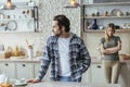 Sad unhappy young european husband with stubble ignores offended wife after scandal in modern kitchen Royalty Free Stock Photo