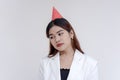 A sad and unhappy young woman looking sideways and wearing a pink party hat. Isolated on a white background Royalty Free Stock Photo