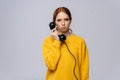 Sad unhappy young woman in stylish yellow sweater talking on retro phone and looking at camera Royalty Free Stock Photo