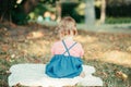 Sad upset baby kid sitting on ground outdoor in park. Child got offended. Upset innocent baby girl does not want to communicate