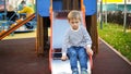 Sad and upset little lonely boy sitting on slide at playground Royalty Free Stock Photo