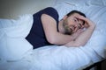 Sad and upset man trying to sleep in bed