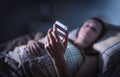 Sad upset woman looking at smartphone at night in bed. Phone call from unknown caller. Sleepless person suffering from stress. Royalty Free Stock Photo