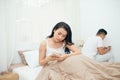 Sad view of young married couple using their mobile phone in bed ignoring each other as strangers in relationship and Royalty Free Stock Photo