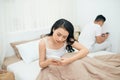 Sad view of young married couple using their mobile phone in bed ignoring each other as strangers in relationship and Royalty Free Stock Photo