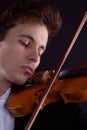 A sad violinist plays a violin on a dark background Royalty Free Stock Photo