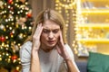 sad Woman alone at home for Christmas and New Year, sitting depressed near Christmas tree on sofa in living room Royalty Free Stock Photo