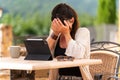 Sad woman crying at a table on a terrace outdoors with a tablet Royalty Free Stock Photo