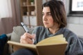 sad woman with diary sitting on sofa at home Royalty Free Stock Photo
