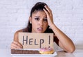 Sad woman on diet holding a sign help resisting temptation to eat chocolate and donuts