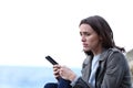 Sad woman holding phone complaining on the beach Royalty Free Stock Photo