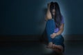 sad woman hug her knee and cry sitting alone in a dark room. Depression, unhappy, stressed and anxiety disorder concept Royalty Free Stock Photo