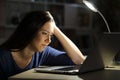 Sad woman looking at laptop at night at home
