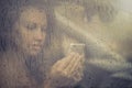 Sad woman looking in the mobile phone and reading message in the window with rain drop in the car. Royalty Free Stock Photo