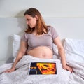 A sad woman looks at the results of an ultrasound for pregnancy lying in her home bed