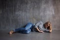 Sad woman lying on the floor. Depression and chronic fatigue. Young beautiful blonde in a gray sweater and jeans Royalty Free Stock Photo