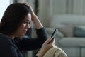 Sad woman reading bad news on phone complaining at home Royalty Free Stock Photo