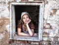 Sad woman in a rustic dress sitting near window in old house feel lonely. Cinderella style Royalty Free Stock Photo