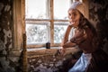 Sad woman in a rustic dress sitting near window in old house feel lonely. Cinderella style Royalty Free Stock Photo