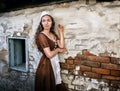 Pensive young woman in a rustic dress standing near old brick wall in old house feel lonely. Cinderella style Royalty Free Stock Photo