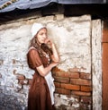 Pensive young woman in a rustic dress standing near old brick wall in old house feel lonely. Cinderella style Royalty Free Stock Photo