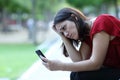 Sad woman in a park checking phone Royalty Free Stock Photo