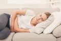 Sad woman with stomach ache on couch at home Royalty Free Stock Photo