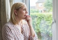 Sad Woman Suffering From Agoraphobia Looking Out Of Window