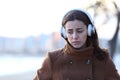 Sad woman walking listening to music alone in winter Royalty Free Stock Photo