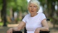 Sad woman in wheelchair deeply sighing sitting outdoor, disability, close-up