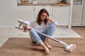 A sad woman with a wireless portable vacuum cleaner in the kitchen. A Royalty Free Stock Photo