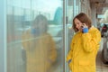 Sad woman in yellow raincoat talking on mobile phone Royalty Free Stock Photo