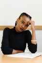 Sad worried African or black American woman holding her forehead with hand at desk