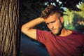 Sad, worried blond young man against tree Royalty Free Stock Photo