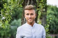 Sad, worried blond young man against tree