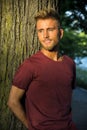 Sad, worried blond young man against tree