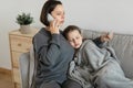 Sad worried european millennial mother calms, takes care of sick teen girl, calls by phone to doctor