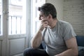 Sad and worried man with grey hair sitting at home couch looking