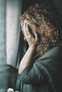 Sad and worried woman side portrait at home in the dark looking outside the window. Worried and lonely female alone indoor. Royalty Free Stock Photo